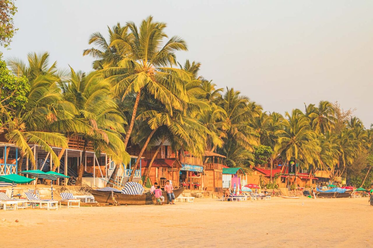 Kolorowe domki na plaży Palolem otoczone palmami o zachodzie słońca – Goa, Indie