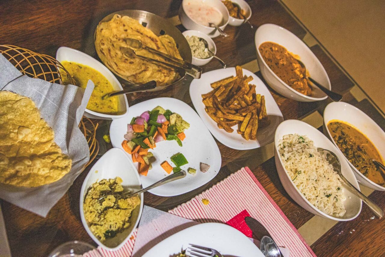 Stół zastawiony tradycyjnymi daniami kuchni południowoindyjskiej w Bamboo Creek Resort w Wayanad, Kerala – curry, ryż, warzywa, chlebki i dodatki.
