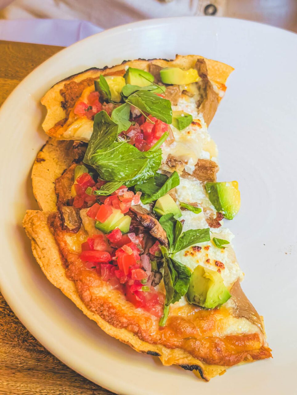 A Tlayuda served at Los Danzantes restaurant in Coyoacán, Mexico City, a traditional Oaxacan dish, presented on a white plate.