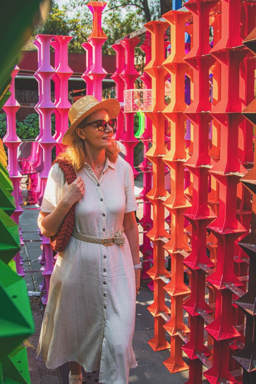A woman walks among colorful art installations in the Coyoacán district of Mexico City, a peaceful moment of everyday life.