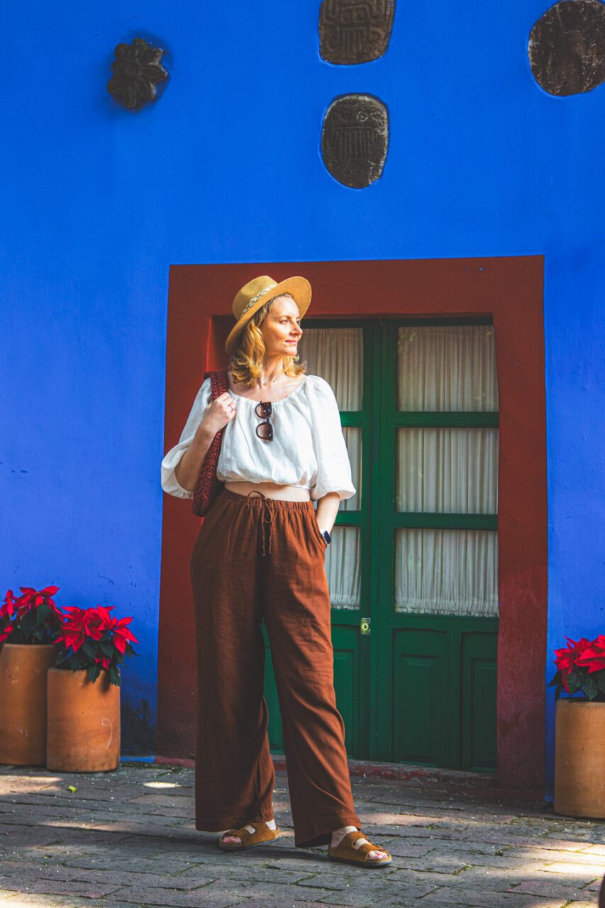 A woman standing by the blue wall of Casa Azul in Coyoacán, Mexico City, a peaceful moment during a visit to the Frida Kahlo museum.