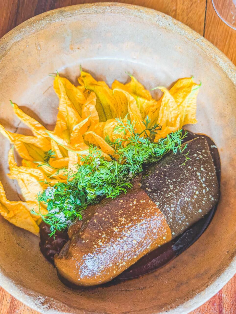 Danie z mole i kwiatami dyni w Levadura de Olla w Oaxaca, podane w glinianej misie