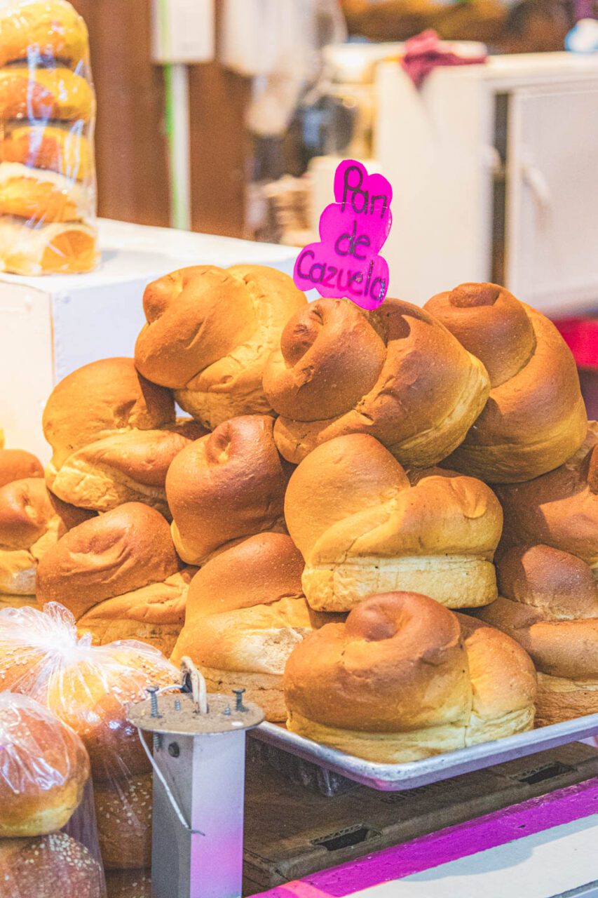 Traditional pan de cazuela at a market in Oaxaca, stacks of bread loaves sold locally.