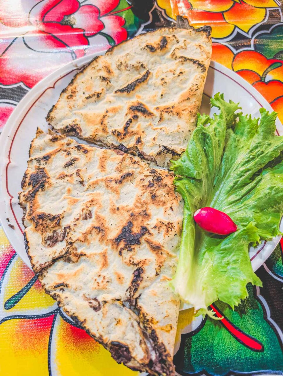 Tlayudas from Tlayudas Los Ánimas in Oaxaca – a crispy corn tortilla with black bean paste, meat, and fresh lettuce.