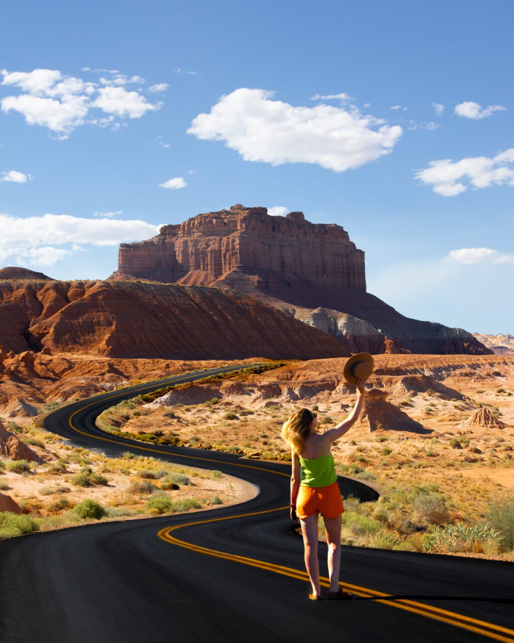 woman with hat on scenic red rock road in Utah Southwest road trip