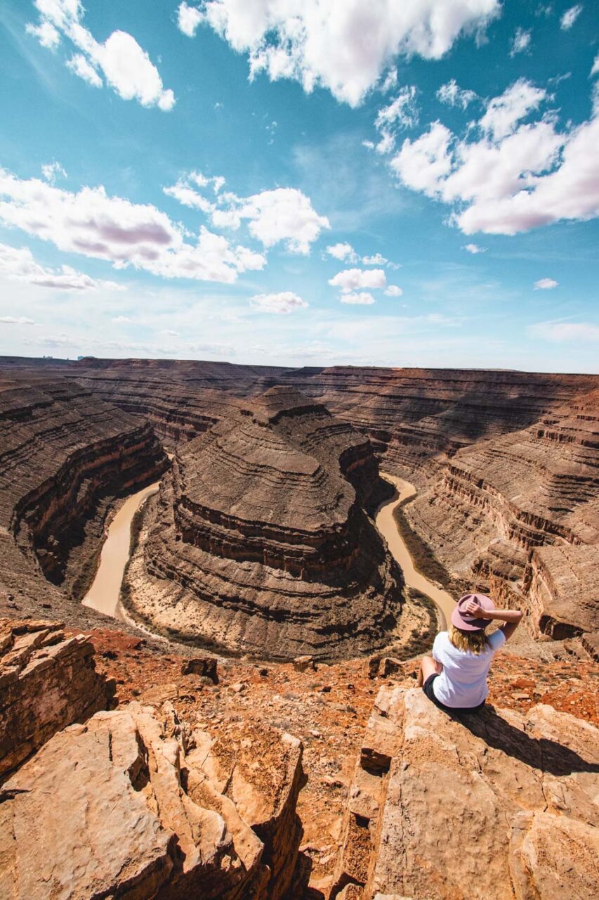 woman sitting at Goosenecks State Park viewpoint Utah river meanders canyon view