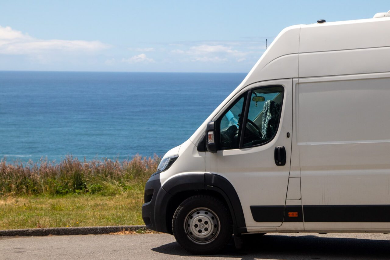 A campervan parked on a cliff overlooking the ocean.