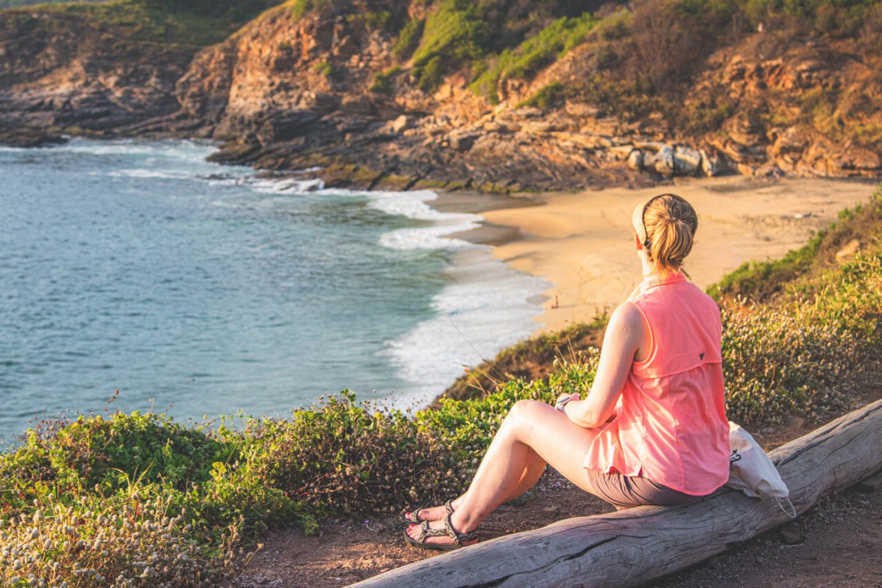 Widok na klify i plażę w Punta Cometa w Oaxaca, kobieta siedząca i patrząca na ocean