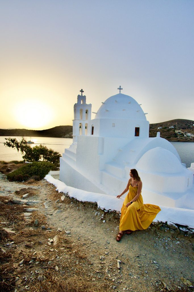 Woman in yellow dress admiring sunset at Agia Irini church, Ios, Greece