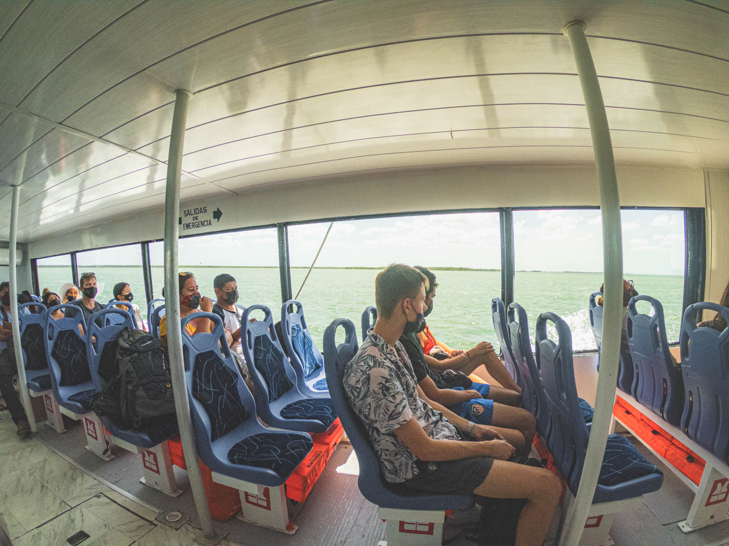 Ferry ride to Isla Holbox - a boat filled with sun, wind, and travelers in tropical shirts. The last step before diving into the island's chill.