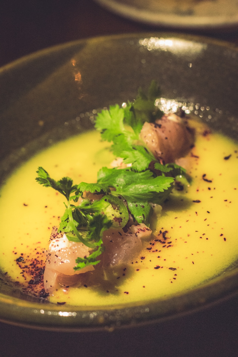 Zbliżenie na elegancko podane ceviche lub tatar z surowej ryby w żółtym sosie owocowym, z kolendrą i przyprawami, w restauracji w Tulum.