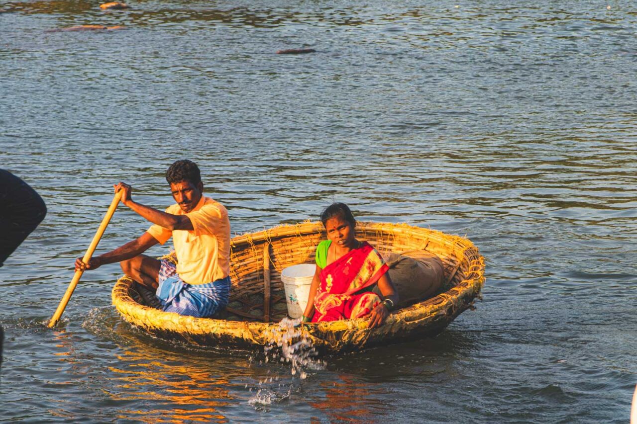 Lokalna para wiosłuje okrągłą bambusową łodzią coracle na rzece Tungabhadra w Hampi w Indiach