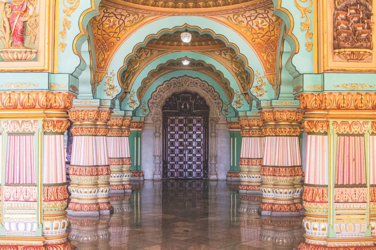 Kolumnowa sala w pałacu Maharadży w Mysore – pastelowe kolory, złote zdobienia i misternie rzeźbione łuki.