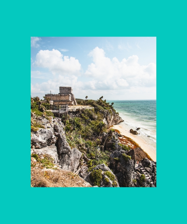 Mayan ruins in Tulum standing on a cliff above the Caribbean Sea, with views of the ocean and rocky shoreline.