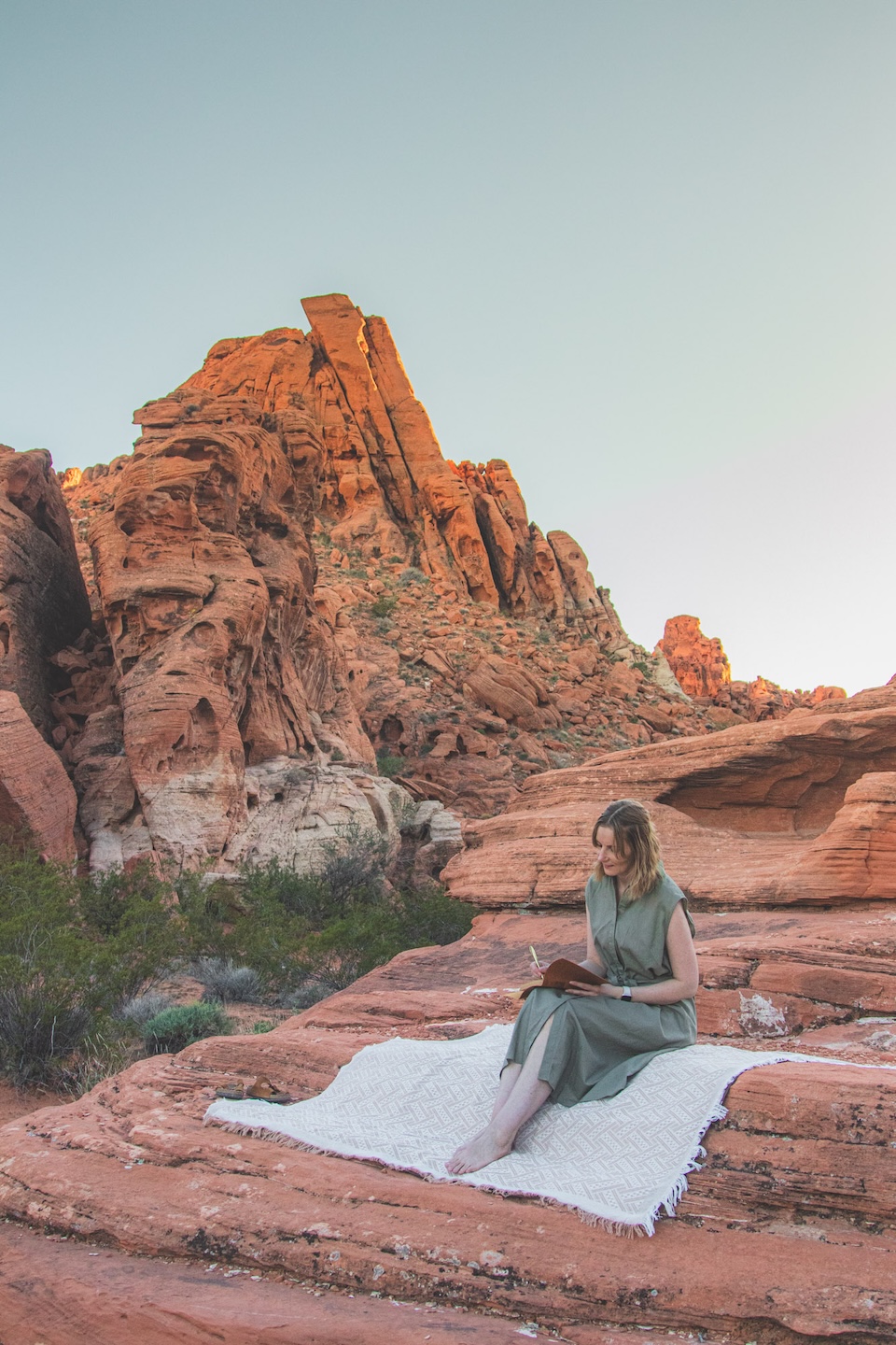 Ania Flik journaling among red desert rocks – a personal ritual on the road.