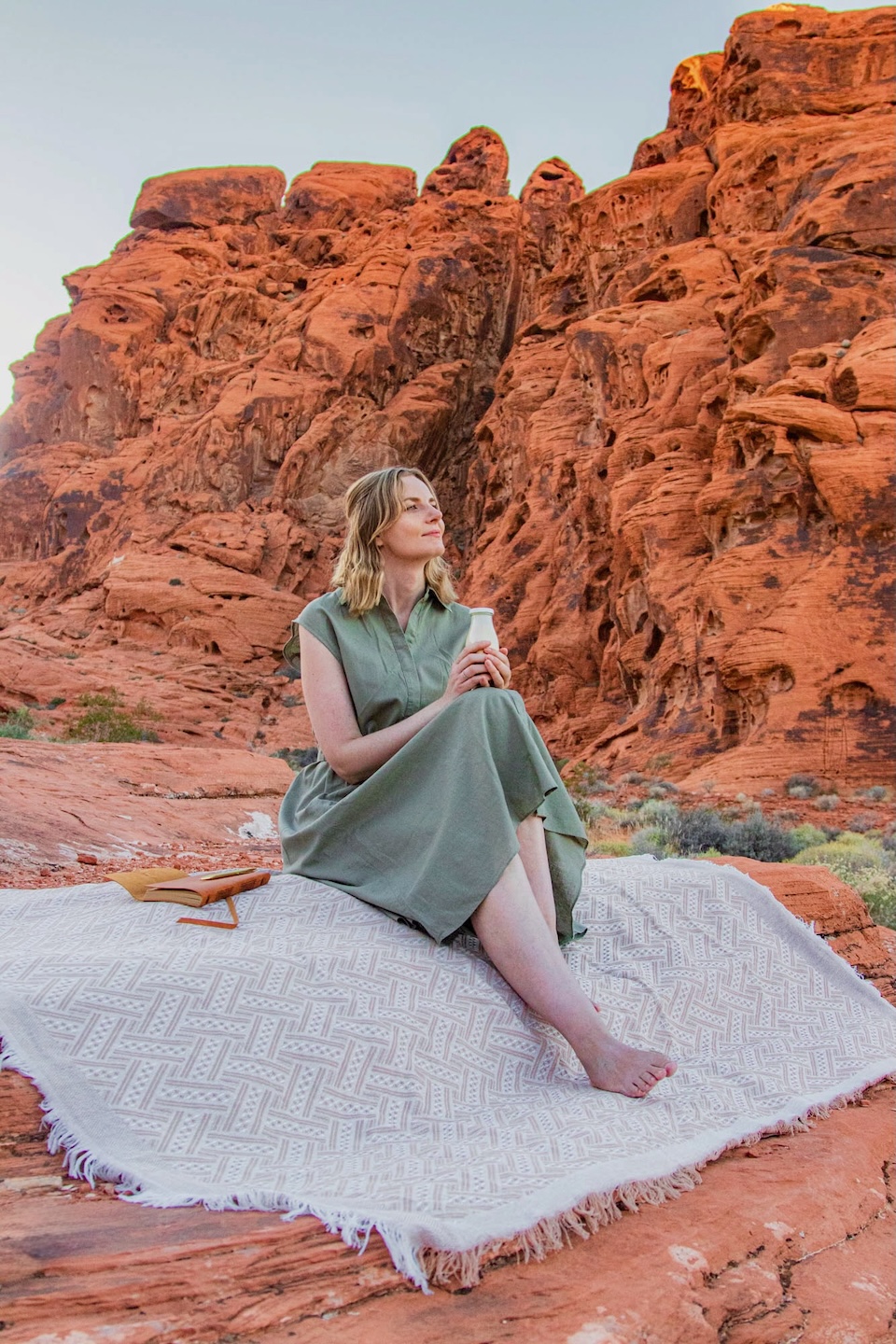 Runaway Ann siedzi na pustyni z butelką Butta i notesem – rytuał pisania, pustynne światło i chwila tylko dla siebie.