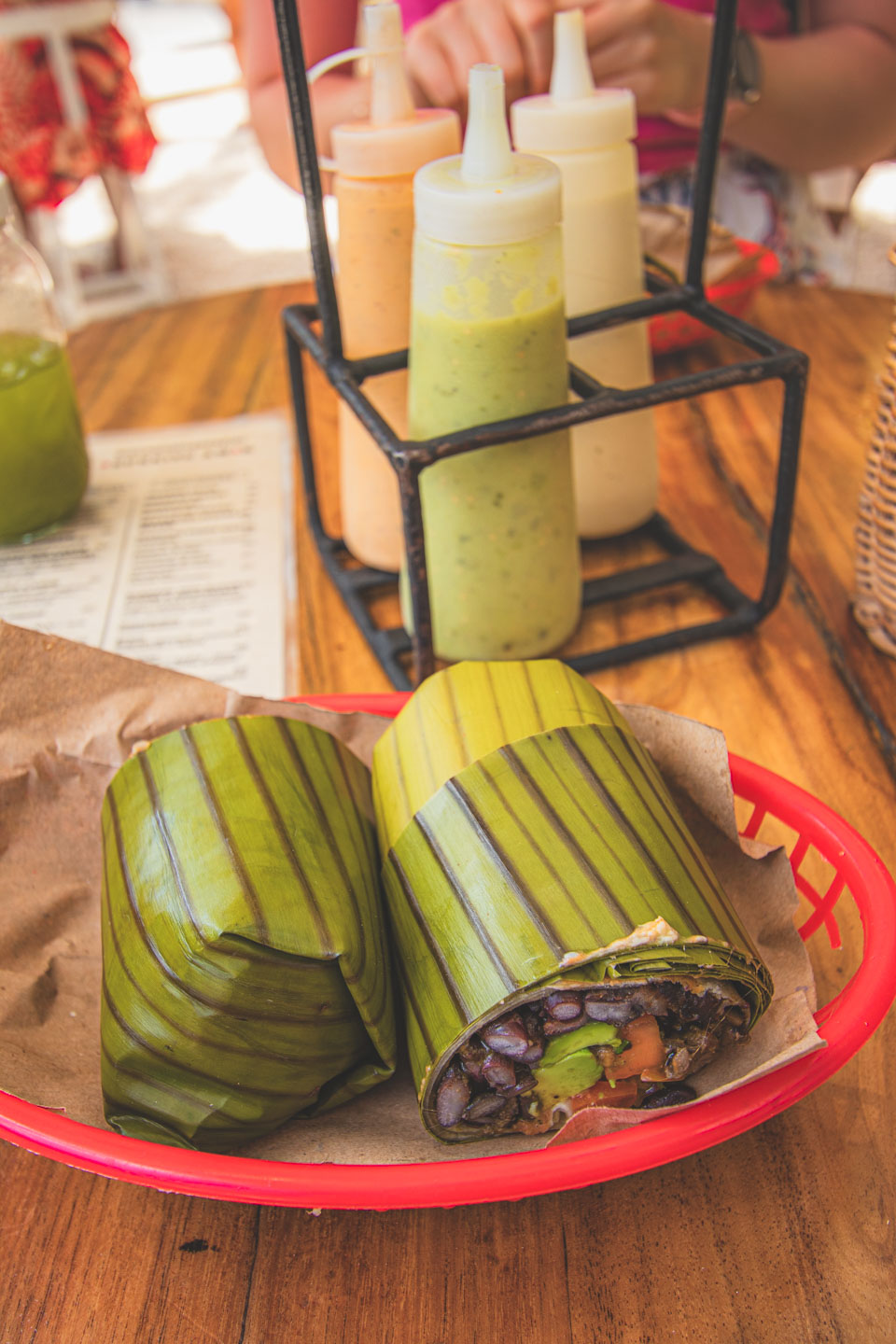 Burrito wrapped in banana leaf with black beans and veggies at Burrito Amor, Tulum – a spot full of salsas and laid-back tropical vibes.
